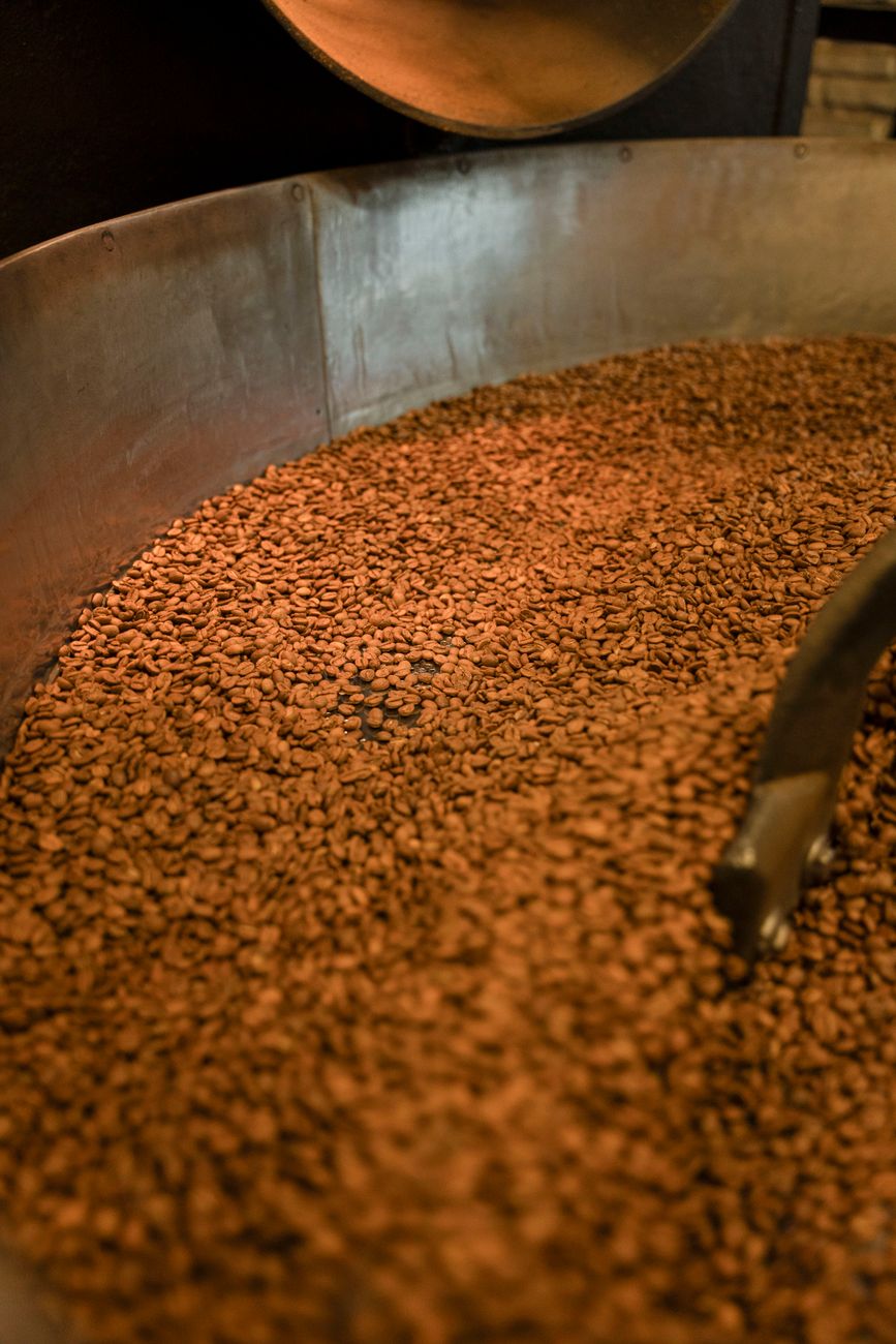 Freshly roasted coffee beans in an industrial roaster, highlighting the rich texture and color.
