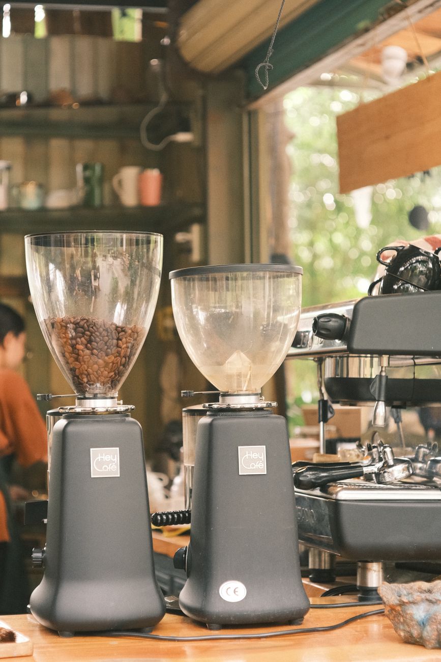 Cozy coffee shop featuring espresso machines and grinders with urban decor.