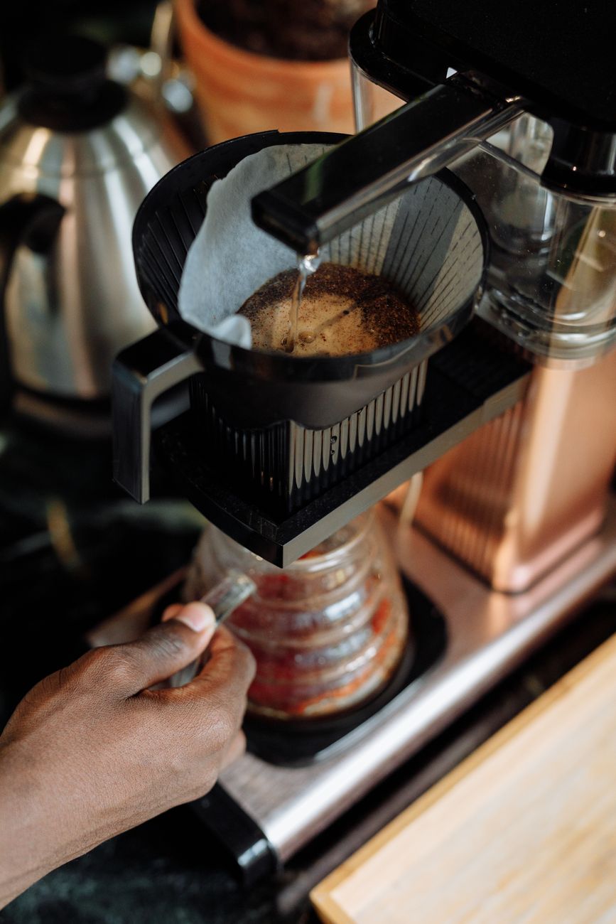 Pour over coffee preparation with hand pouring hot water over ground coffee in a filter.